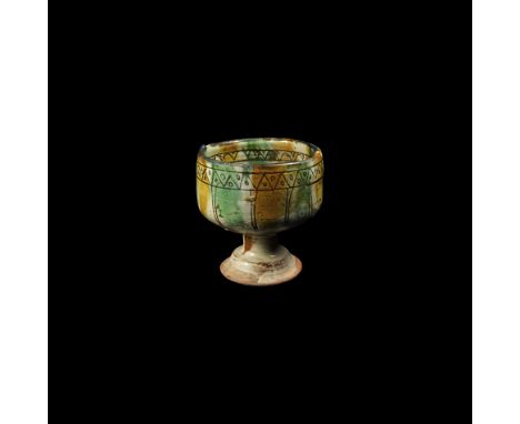 12th-early 13th century AD. A ceramic chalice with carinated body, waisted stem and concave foot, cream glaze with splashed a