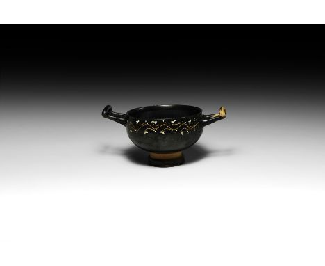 4th century BC. A blackware skyphos with carinated body and two handles with tapering arms leaving the body, bridged by an in