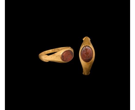 3rd century AD. A carnelian gemstone with intaglio temple flame motif, set in later gold finger ring with facetted shoulders;