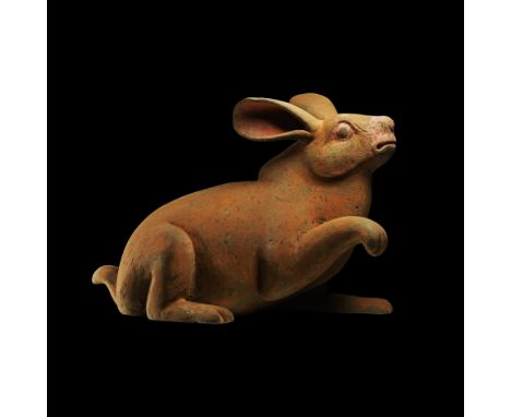 Han Dynasty, 206 BC-220 AD. A ceramic rabbit modelled in the round with raised right foreleg and paw, ears held aloft and bac