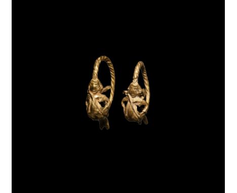 5th-3rd century BC. A matched pair of gold earrings, each a twisted suspension hoop attached a nude figure of Eros with small