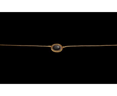 Early 1st century BC. A gold domed oval-shaped pendant set with imitation agate eye glass inlay, applied beads at the base of