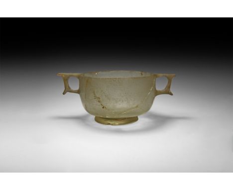 3rd-1st century BC. A clear glass skyphos with bulbous carinated body, integral ring handles formed between projecting plates