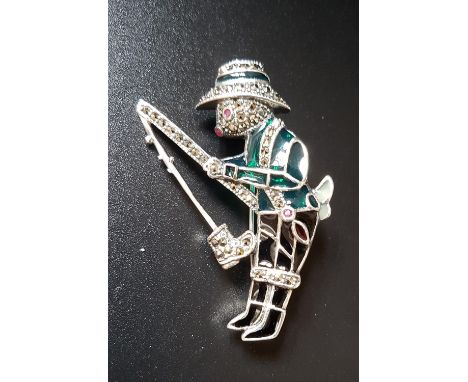 RUBY, MARCASITE AND ENAMEL DECORATED SILVER BEAR BROOCHthe bear modelled as a fishesman, with ruby eye nose and belt detail, 