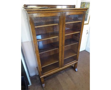 An Oak Glaze Fronted Four Shelf Book Case. The book case has four adjustable shelves with a carved base with stretcher, appro