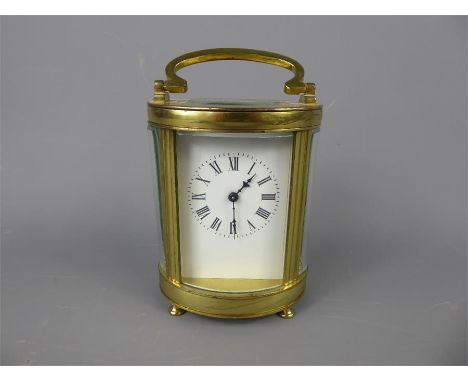 A French Brass Carriage Clock, within an oval case, white enamel face with Roman dial, approx 18 x 13 cms.