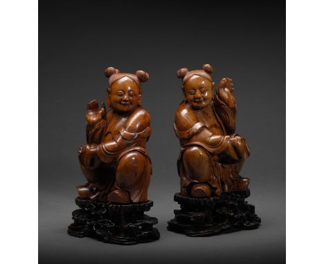 PAIRE DE STATUETTES DE GARÇONS ASSIS EN HUANGHUALIMilieu de la dynastie Qing (1736-1820)A PAIR OF HUANGHUALI FIGURES OF SEATE