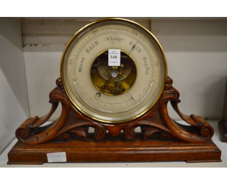 A Victorian aneroid barometer by Baker of London, mounted on a carved oak support.