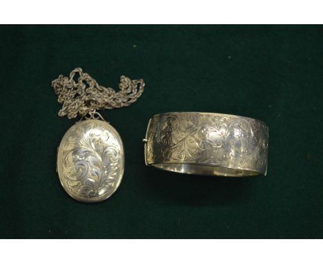 A silver bangle and a large silver locket with engraved decoration.