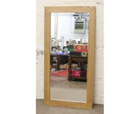 A large light oak framed bevel edged wall mirror.