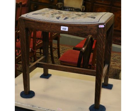 An Edwardian oak piano stool with needle work upholstered seat.