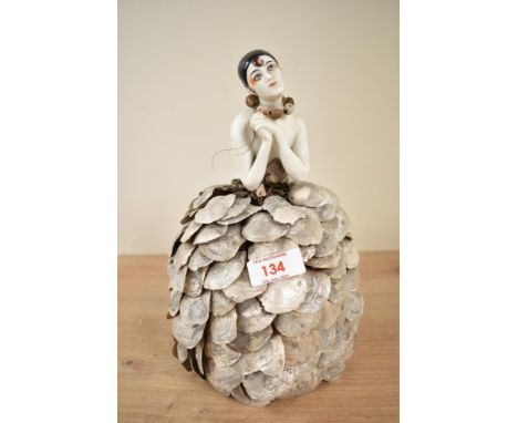 An early 20th century porcelain half-doll with shell skirt, h23.5cm