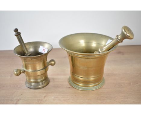 A solid brass pestle and mortar, h11.5cm, sold together with a similar pestle, (2)