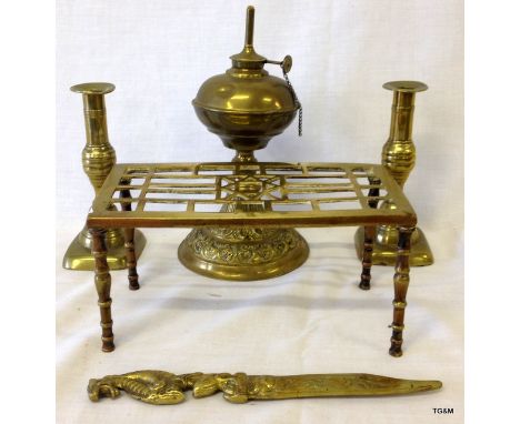 A brass oil lamp, a pair of brass candlesticks, a brass trivet and a brass paper knife