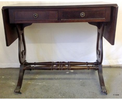 A Mahogany sofa table with 2 drawers with harp shape support and claw casters