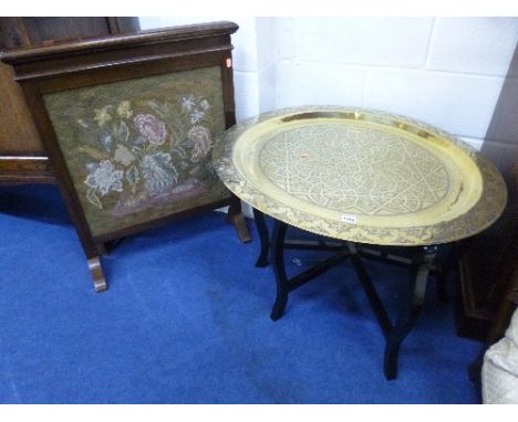 A BRASS TRAY TOP TABLE, with folding ebonised stand and a firescreen with inset needlework panel (2)