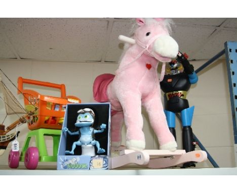 A CHILD'S ROCKING PINK UNICORN, a boxed 'Crazy Frog', a child's toy supermarket trolley and contents and a robot