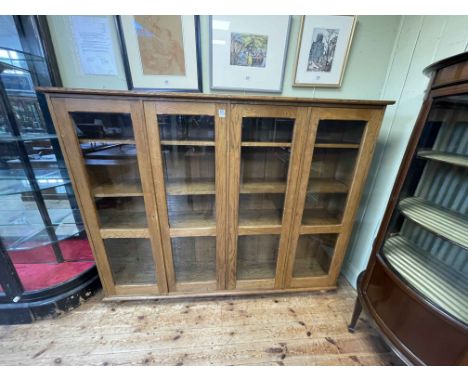 Oak glazed panel four door bookcase with six adjustable shelves, 151cm by 188cm by 39cm.