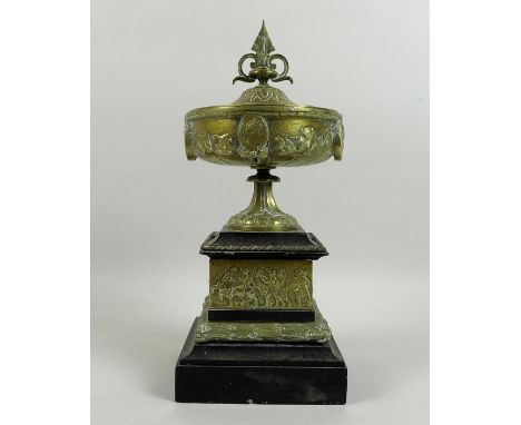 A Victorian cast brass decorative urn, in Greek style, with finial to cover, cast decoration of profile portrait busts, leave