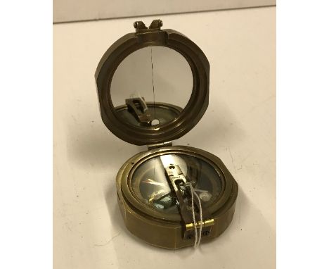 A modern reproduction heavy brass Brunton compass bearing label inscribed "Makers to The Queen London 1920"