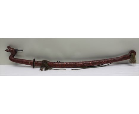 A FIRST QUARTER 20TH CENTURY JAPANESE RED LACQUER COVERED SWORD & SCABBARD, formed as a scaley dragon, the handle terminated 