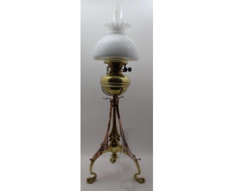 AN ARTS & CRAFTS DESIGN BRASS & COPPER OIL LAMP, raised on triform base, with brass reservoir, two chimneys, and white opaque