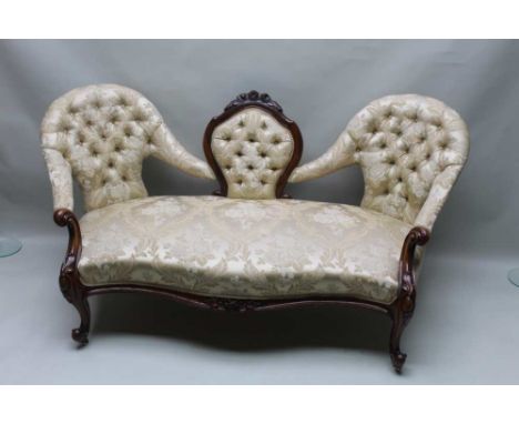 A VICTORIAN WALNUT SHOW WOOD FRAMED CONVERSATION SETTEE, having carved shield shaped back central buttoned section, flanked b