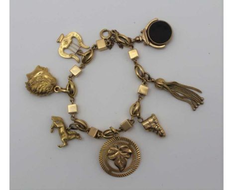 A YELLOW METAL CHARM BRACELET, attached a reversible fob, boot, portrait head of a lady, a lyre, horse, boot, etc. gross weig