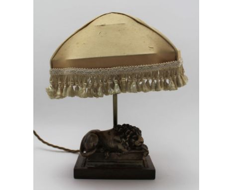 A TABLE LAMP the base mounted with a carved soapstone lion, on mahogany base with shade, 32cm high overall 
