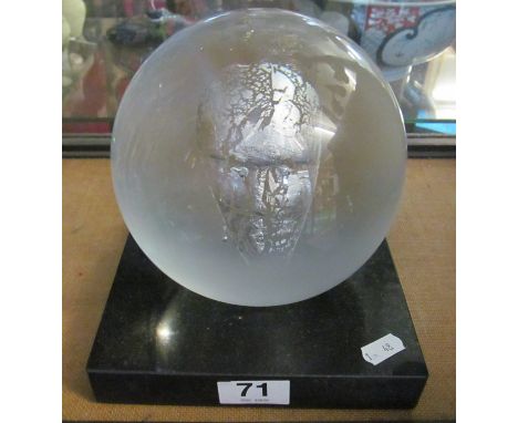 A Kosta Boda glass globe ornament with floating mask  7” square base and 7.5” high