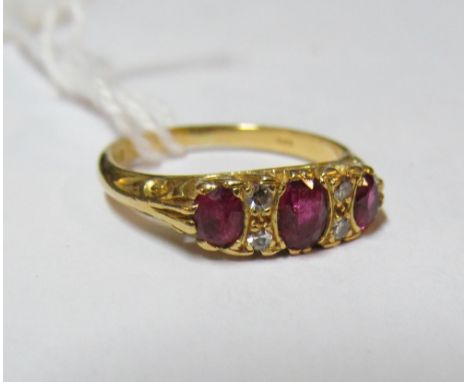 A three stone ruby ring and four small diamonds on 18ct gold band 3.3gm, size K/L