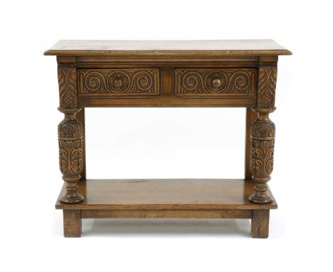 A Jacobean style oak side table, the moulded top over two carved frieze drawers, carved supports, a stretcher shelf and stile