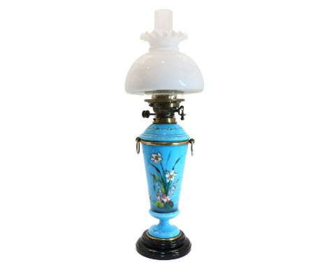 A blue glass oil lamp, late 19th century, painted with flowers below double burners below an opaque shade and a funnel, 42cm 