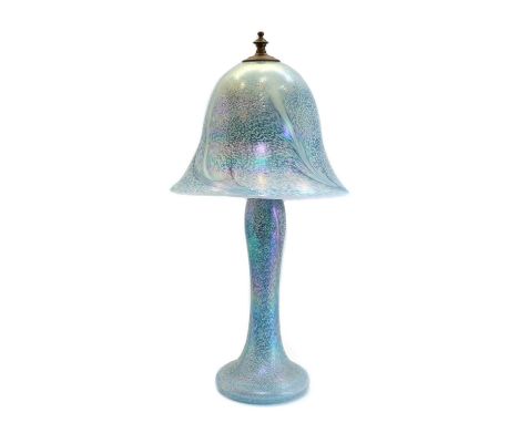 An iridescent studio glass table lamp, in the manner of Tiffany, with a bell form shade, over a tapered column, and spread fo