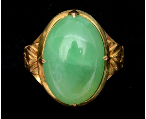 A yellow coloured metal and oval jade ring  See illustration