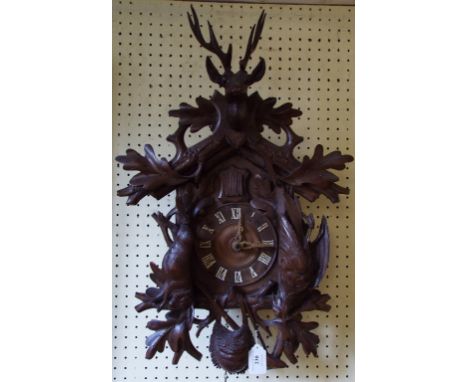A cuckoo wall clock, with Roman numerals, carved deer, dead game and foliage, 55 cm high