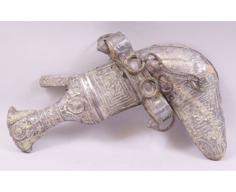 A 19TH CENTURY OMANI JAMBIYA SET, the curved blade 18.5cm with raised metal ridge, with white metal filigree work hilt, conta