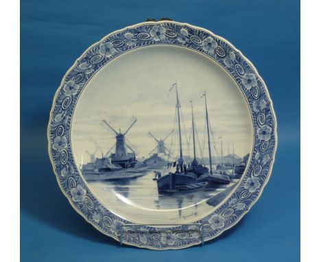 A large Dutch Delft Charger, with gadroon shaped edges, hand painted in blue tones with a scene of Delft with sailing boats a