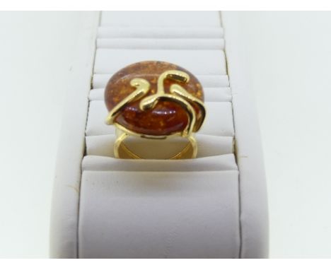 A contemporary 18ct yellow gold and amber Ring, the circular amber front with and applied abstract gold overlay and plain gol