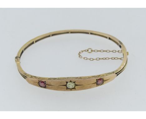 A 9ct gold narrow hinged Bangle, with flared front, gypsy set in the centre with a diamond and with a pink stone on either si