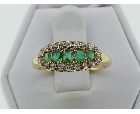 An attractive emerald and diamond Ring, the centre set with five emeralds, with yellow gold tooling around and a border of ei