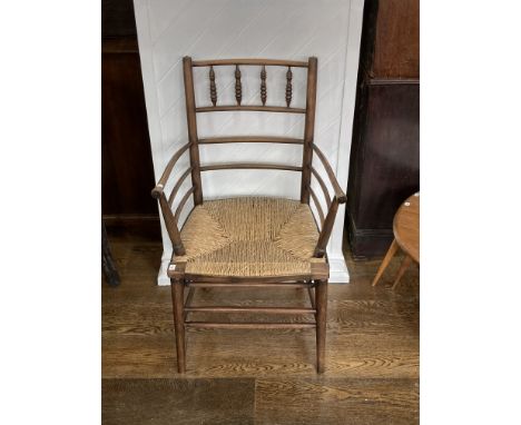 A late 19thC beech Sussex Elbow Chair, the ladder back with spindle gallery to top rails, above envelope rush seat, raised on