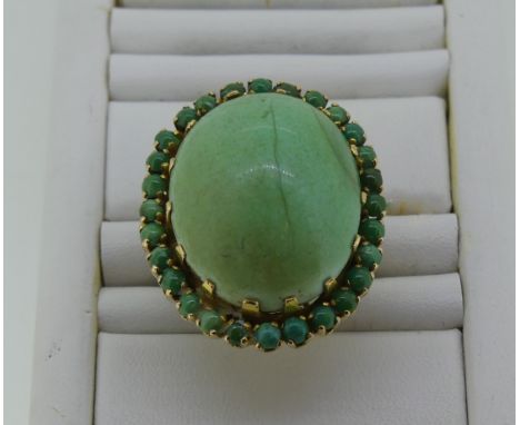 A large turquoise Dress Ring, the oval cabochon central stone, 24mm long, with a border of circular stones around, all mounte