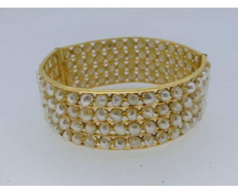A hinged Bangle, formed of four rows of cultured pearls within a ropework frame, unmarked but tested as 18ct gold, 22mm wide,