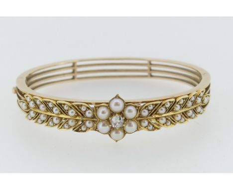 An attractive Edwardian seed pearl and diamond Hinged Bangle, the front set with a central flowerhead with diamond centre, wi