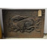A cast iron fire back depicting a dragon.