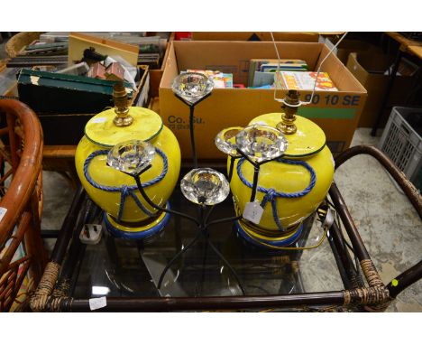 A tea light holder and a pair of yellow pottery table lamps.