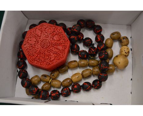 A Chinese cinnabar style box and cover and two decorative bead necklaces.