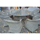 A good large rattan style circular garden table with eight armchairs to include cushions.