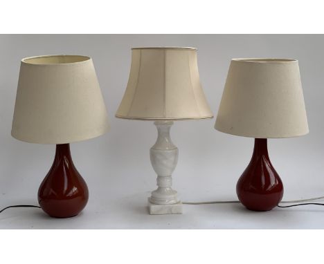 A pair of red glazed ceramic table lamps, approx. 36cmH to top of light fitting; together with a turned marble table lamp on 